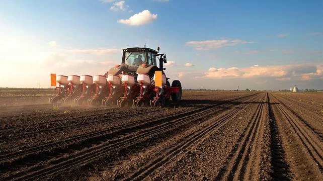 Máquina agrícola fazendo o plantio de sementes no solo, que podem ser tratadas com insumos biológicos.