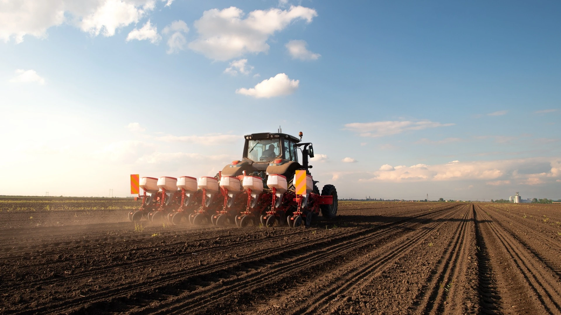 Fazendeiro com trator semeando - plantando culturas em um campo agrícola.