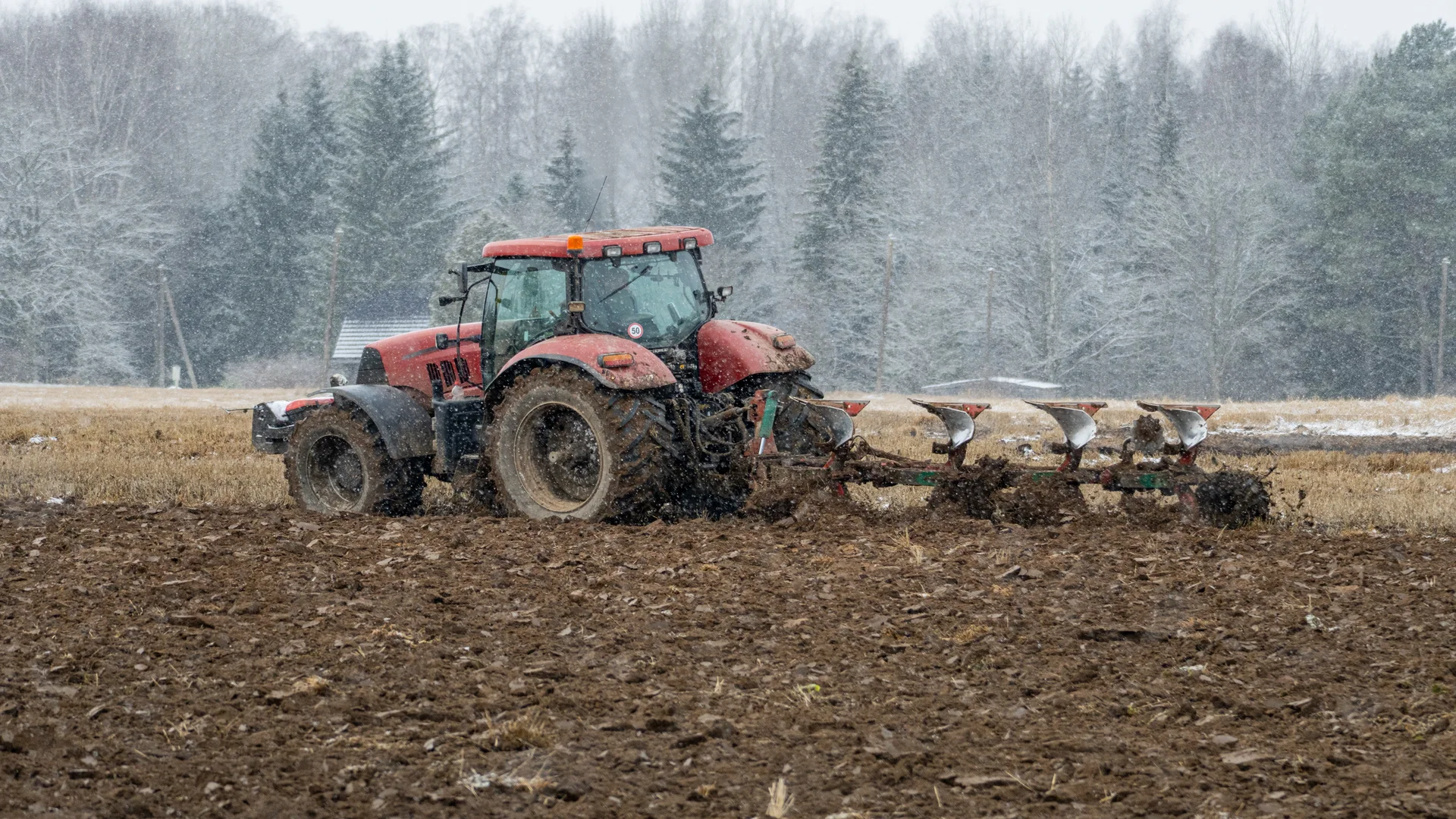 Trator Vermelho Arando Campo em Cascata de Neve de inverno Leve