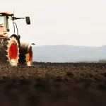 Trator espalhando fertilizantes no campo.