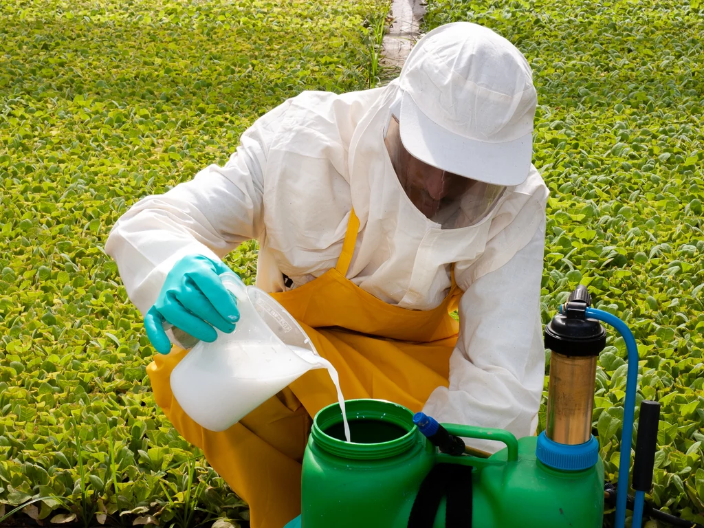 Agricultor com epi fazendo o enchimento de um recipiente com bioinsumos 